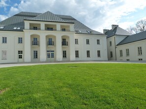 Un grand bâtiment blanc à la façade symétrique, doté de nombreuses fenêtres et d’une entrée centrale avec une porte.