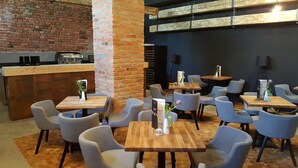 Un restaurant avec un mur en briques, des tables en bois et des chaises grises.