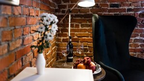 Un mur de briques, une table avec une bouteille et des verres, et une chaise.
