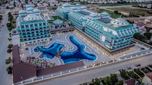 A hotel with multiple blue-domed buildings, a central swimming pool, and a parking area. - Sensitive Premium Resort & Spa - All Inclusive (Serik)