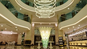 A multi-level atrium with a central spiral chandelier, reflective floors, and glass railings. - Sensitive Premium Resort & Spa - All Inclusive (Serik)