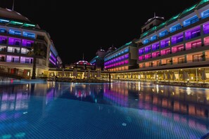 Un hotel con una piscina grande, varios balcones y un diseño arquitectónico moderno.