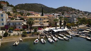 Una cittadina costiera con un porto turistico, edifici con balconi e uno sfondo collinare.