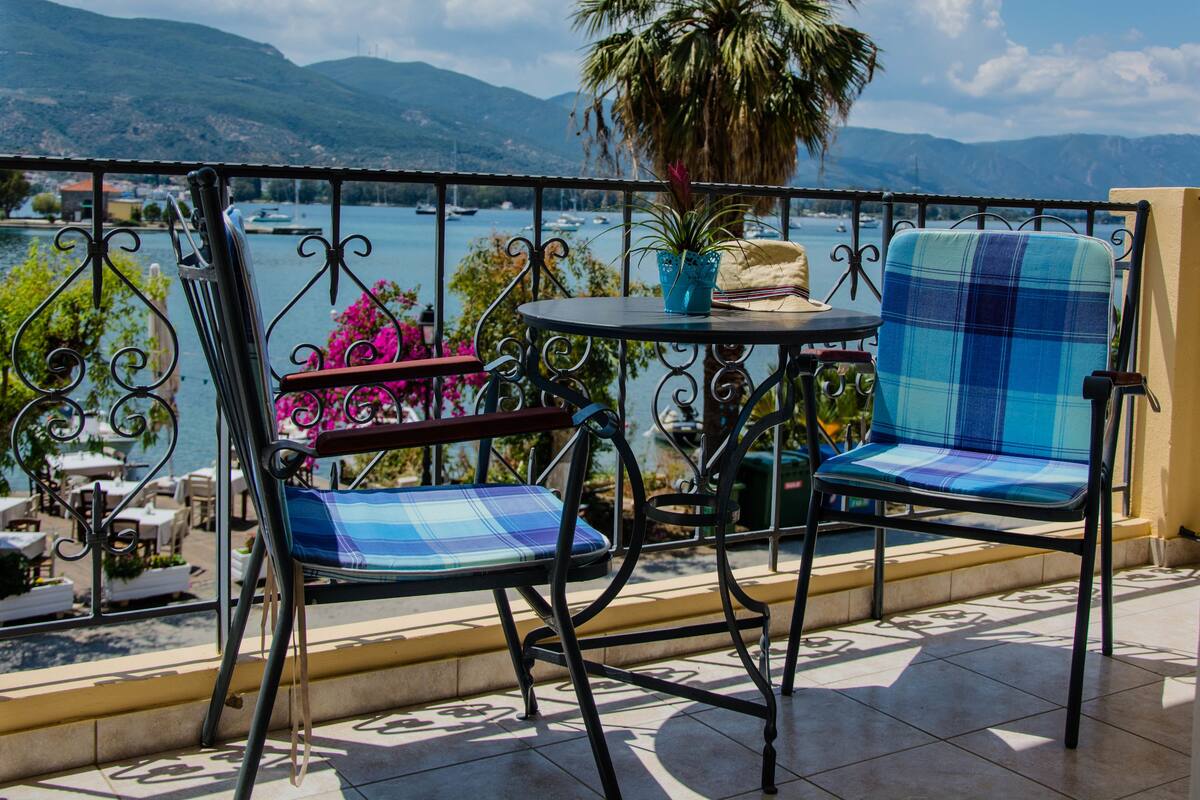 A balcony with two chairs, a table, and a potted plant.