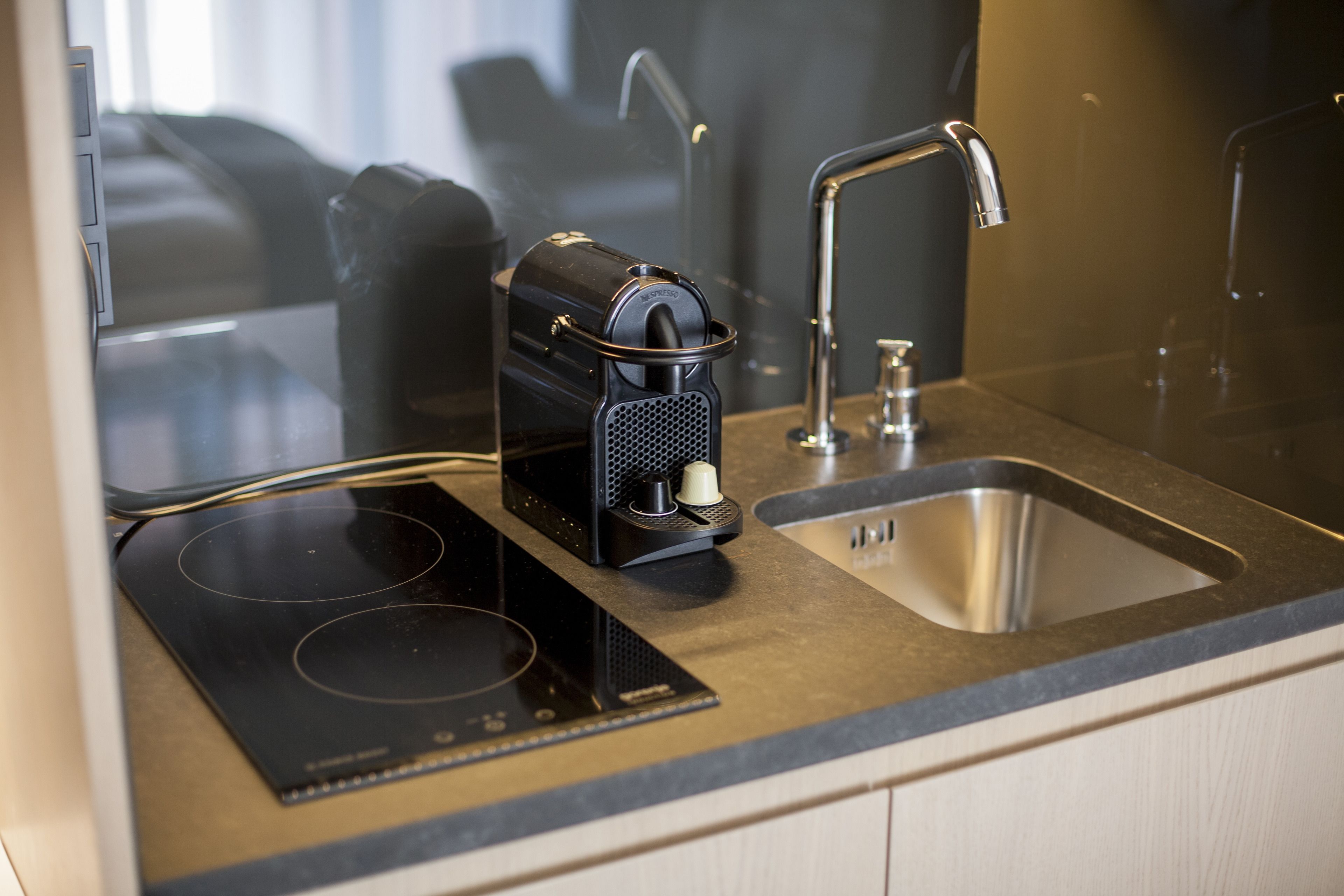 A modern kitchen with a built-in induction cooktop, a coffee maker, and a stainless steel sink.