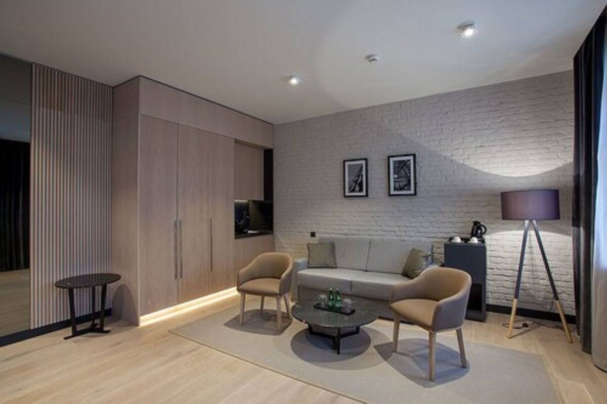 Una sala de estar moderna con un sofá, dos sillones, una mesa de centro y una lámpara.