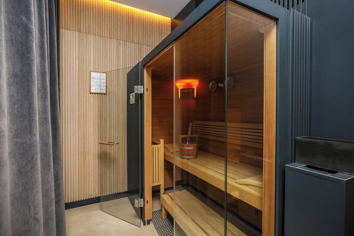 Un cuarto de sauna con bancos de madera, pared de madera y puerta de vidrio.