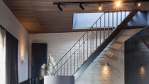 Un salon moderne avec un escalier, un canapé, une lampe sur pied et un tableau accroché au mur.