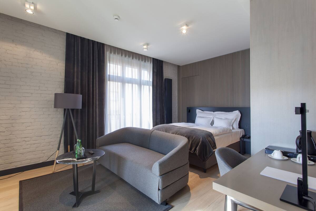 Una habitación de hotel moderna con sofá, una mesita, una cama y un escritorio.