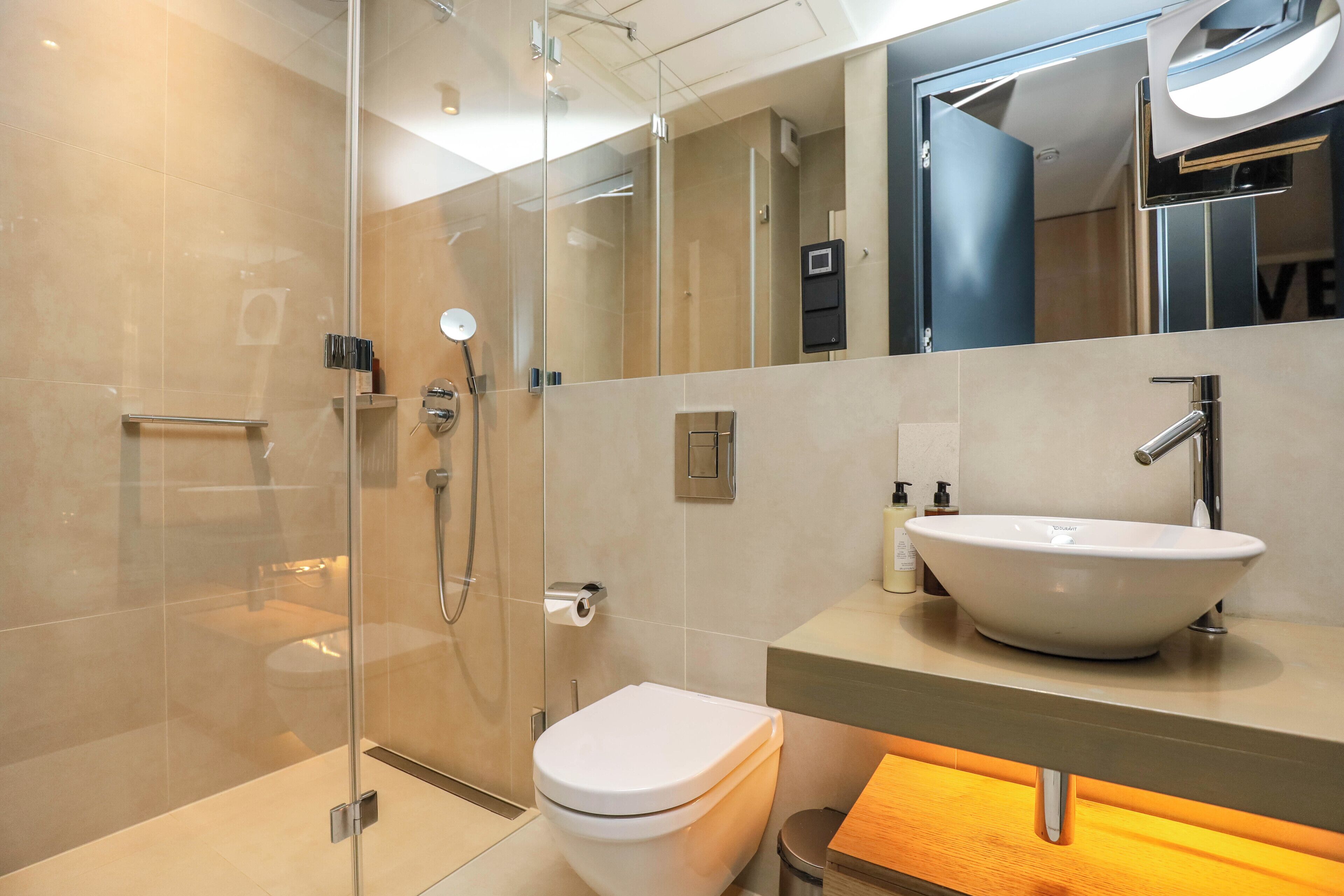 A modern bathroom with a glass-enclosed shower, a white toilet, and a wooden vanity with a vessel sink.