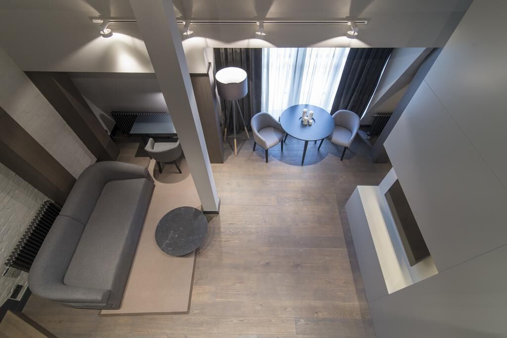 Ein modernes Interieur mit einer Couch, einem runden Tisch mit Stühlen und einem großen Fenster mit Vorhängen.