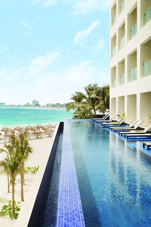 A poolside view with a clear sky, a beach, and a hotel building. - Turquoize at Hyatt Ziva Cancun - Adults Only - All Inclusive (Cancun)