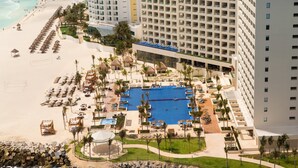Un resort con una grande piscina, lettini in spiaggia e un litorale roccioso.