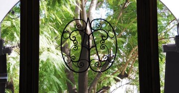 Um portão de ferro forjado com um design decorativo, diante de um cenário de folhagem verde exuberante.
