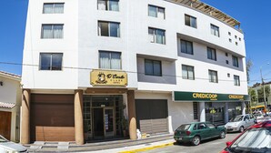 A multi-story hotel with a modern facade, featuring a prominent 'D'Carla Class Hotel' sign, two 'CREDICOOP' storefronts, and a parking lot with several cars.