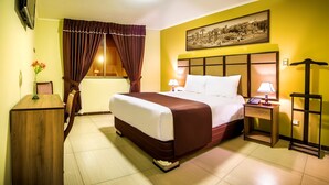 A hotel room with a bed, bedside tables, a lamp, a picture on the wall, and a window with curtains.