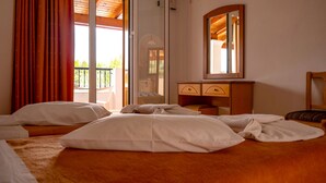A hotel room with a bed, a wooden dresser, a mirror, and a balcony with red curtains. - Tria Adelphia (Corfu)