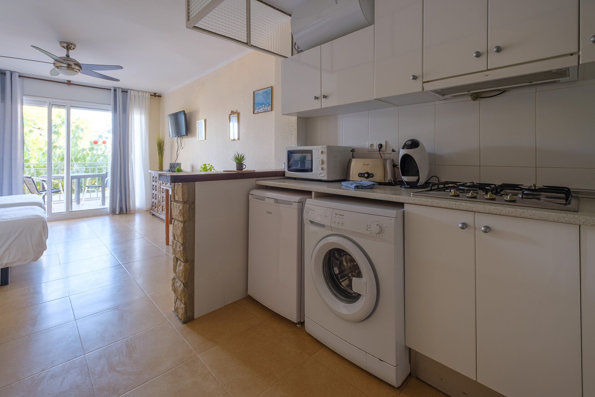 Una cocina compacta con lavadora, microondas y cocina a gas.