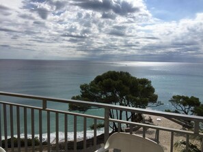 A balcony with a view of the sea, a sandy beach, and some trees. - Apartamentos Deauville - 1 (Mont-roig del Camp)
