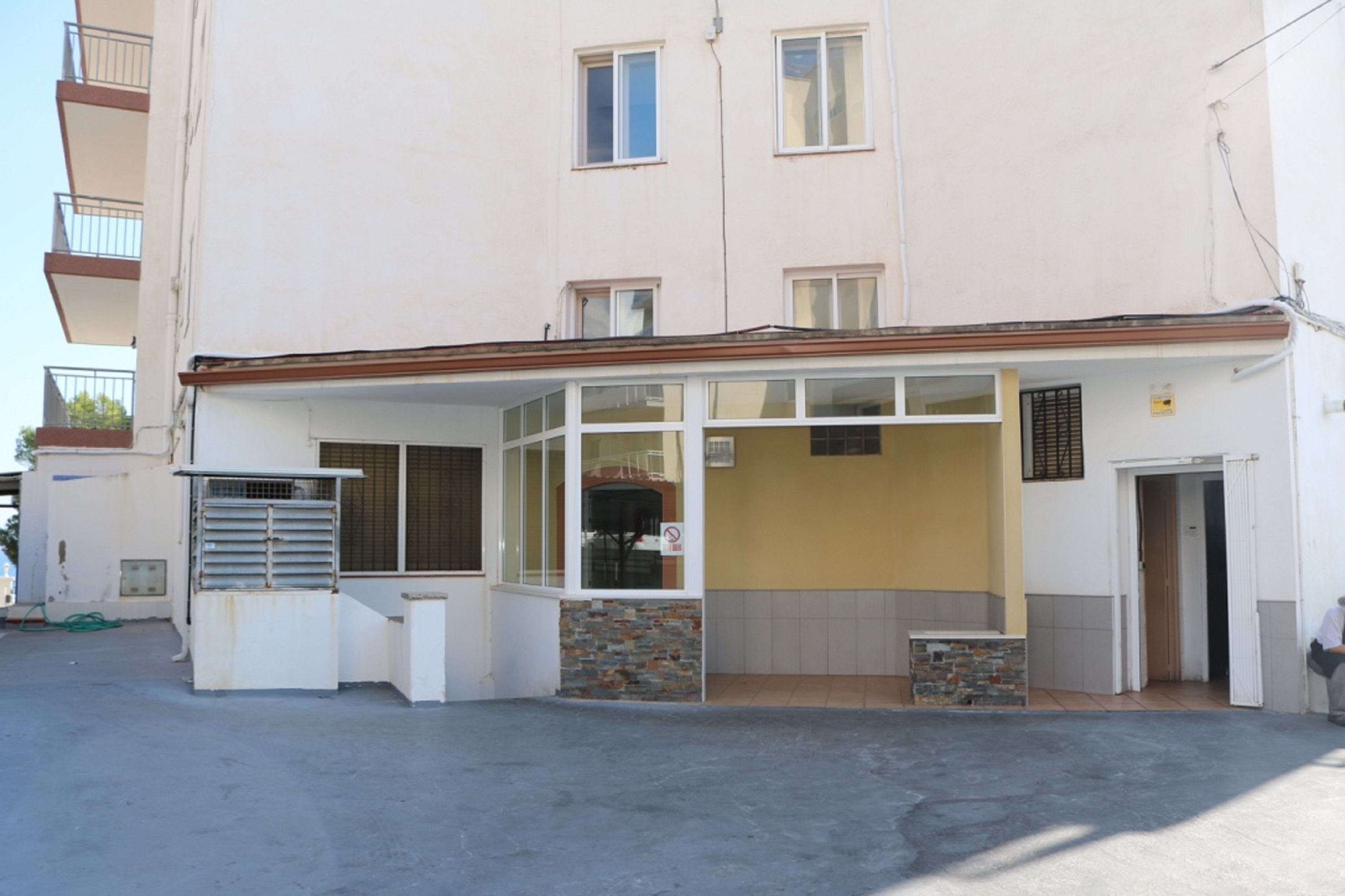 Un bâtiment à deux étages doté d’une entrée couverte et d’un petit espace extérieur aménagé pour s’asseoir.