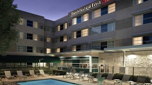Un hôtel doté d’une piscine, d’un espace extérieur aménagé et d’une façade en pierre.