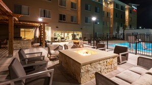 An outdoor patio with a stone fire pit, seating, and a pool. - Residence Inn by Marriott Austin Airport (Austin)