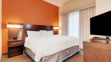 Una habitación de hotel con una cama grande, mesitas de noche, televisión y una ventana con cortinas.