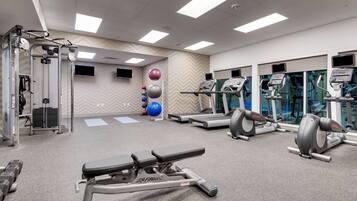 Et fitnesscenter med løbebånd, styrketræningsudstyr og træningsbolde.