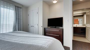 Una habitación de hotel con cama, televisión en una cómoda y baño visible a través de una puerta abierta.