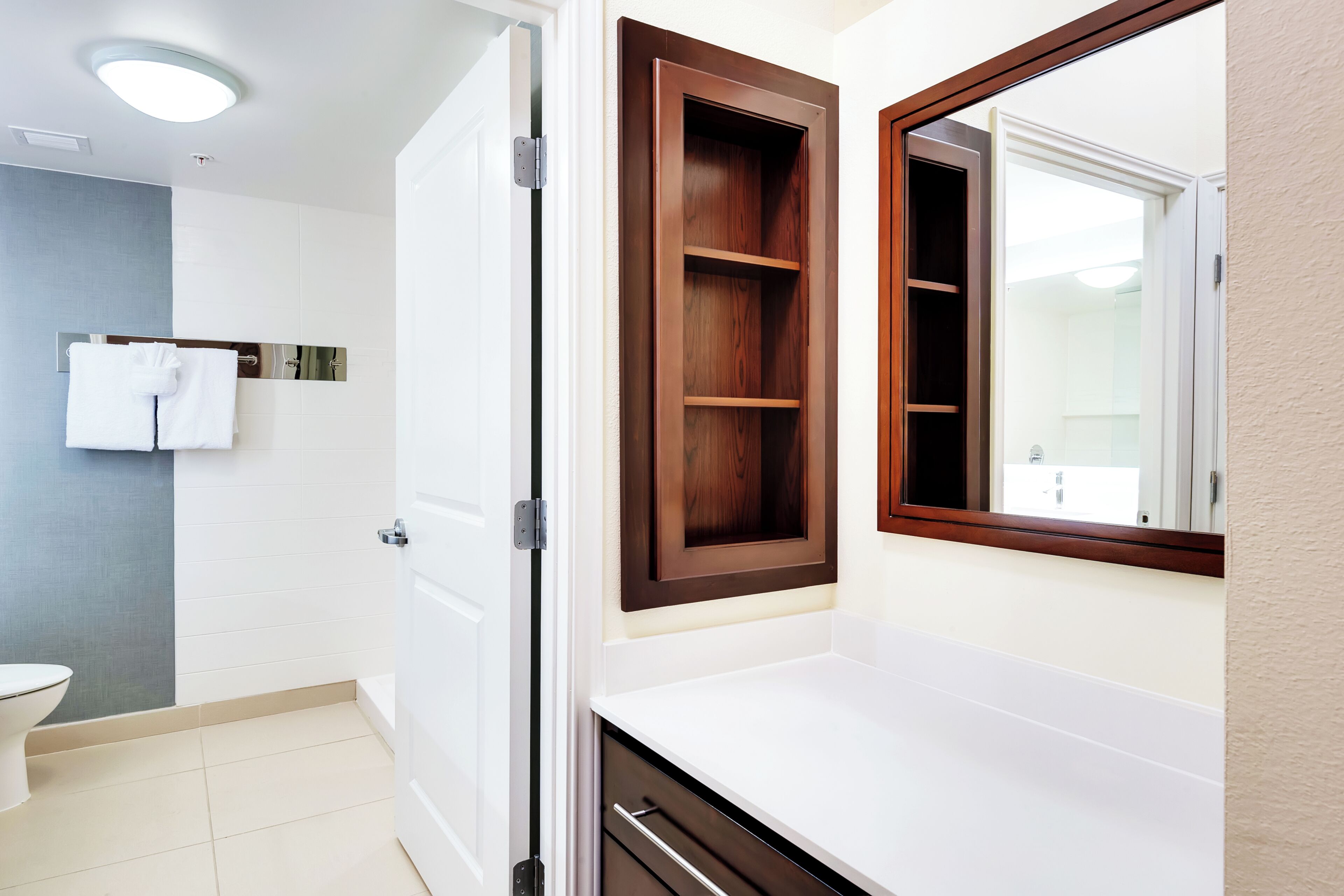 A bathroom with a white toilet, a white sink, a mirror, and a wooden cabinet.