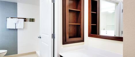 A bathroom with a white toilet, a white sink, a mirror, and a wooden cabinet.
