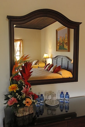 A hotel room with a large mirror reflecting a bed, a nightstand with a vase of flowers, and a painting on the wall. - Hotel Palacio Real Granada (Granada)