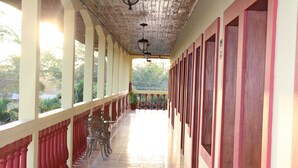 A covered corridor with a tiled floor, red balustrades, and a row of doors on one side. - Hotel Palacio Real Granada (Granada)