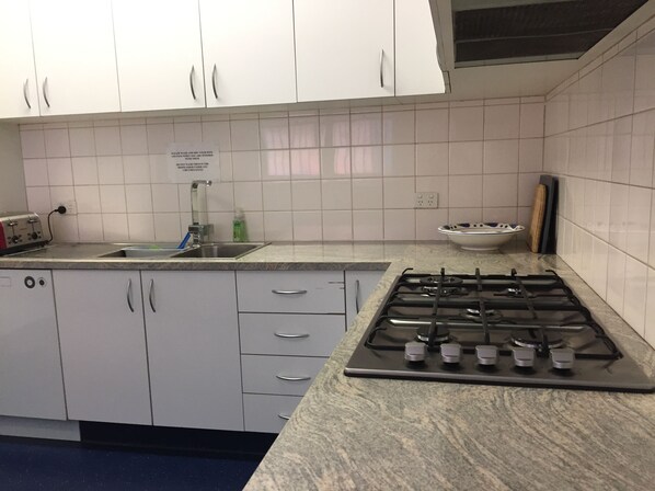 A kitchen with white cabinets, a sink, a gas stove, and a toaster. - SmartStay Melbourne (Windsor)