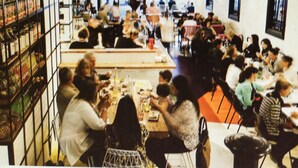 A crowded indoor space with tables and chairs, shelves with items, and a high ceiling with hanging lights. - SmartStay Melbourne (Windsor)