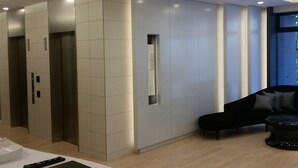 A modern interior with a reception desk, a black sofa, and a staircase. - Meitetsu Inn Hamamatsucho (Tokyo)