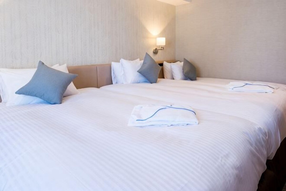 A hotel room with two beds, a headboard, and a wall-mounted light fixture.