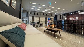 A hotel lobby with a white sofa, a wooden table, and a bar area. - Hotel Atrium Seoul Jongno (Seoul)