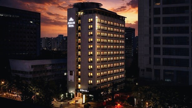 A multi-story hotel with a prominent sign on the side, surrounded by other buildings. - Hotel Atrium Seoul Jongno (Seoul)