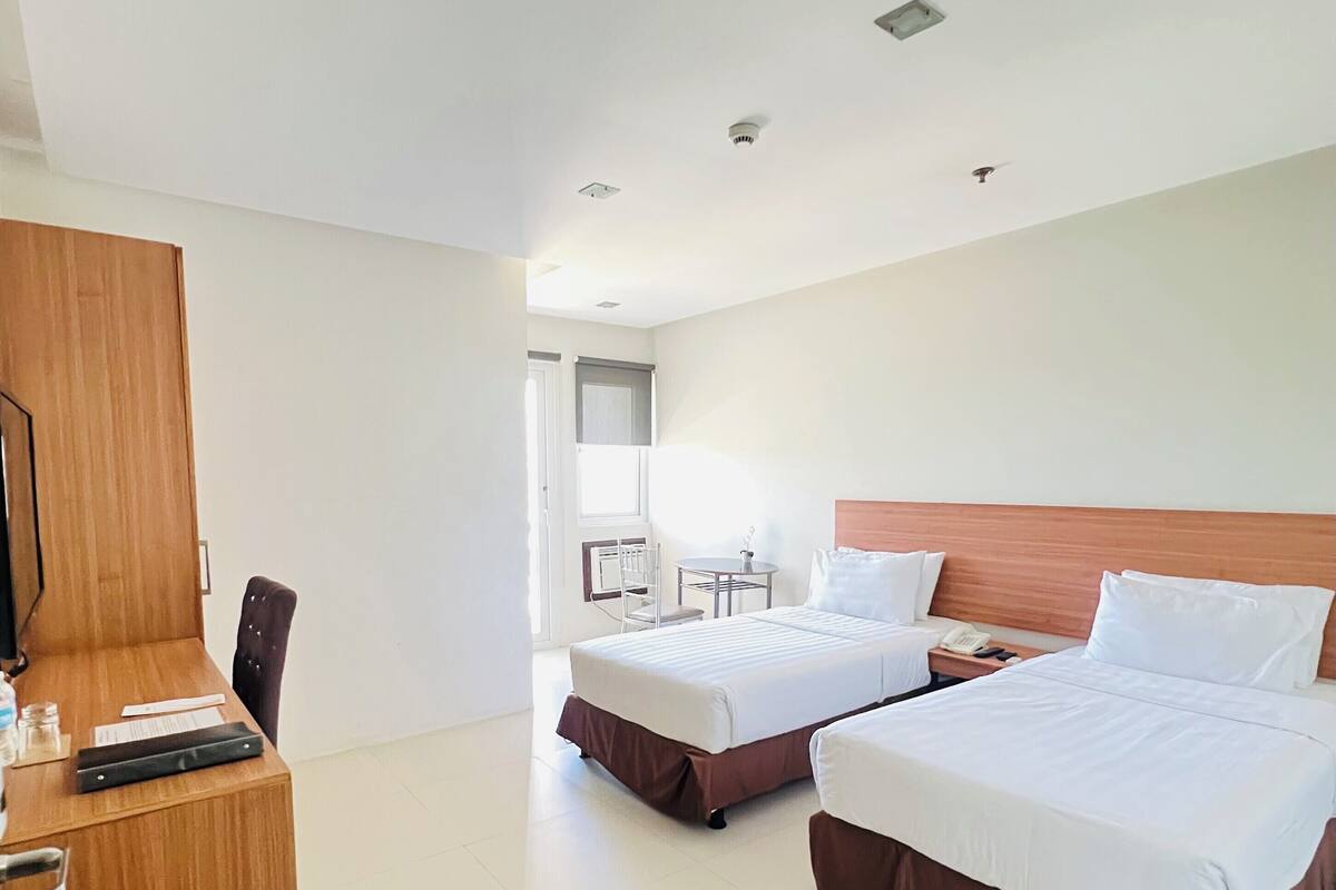 Une chambre d’hôtel avec deux lits, un bureau et une chaise.