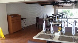 Een eetgedeelte met een hoge tafel voor vier personen, stoelen, een houten kast en een klein krukje.