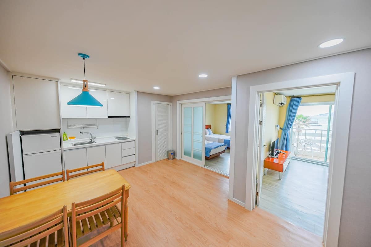 A modern kitchen with white cabinets, a wooden dining table, and a blue pendant light.