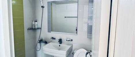 A bathroom with a shower, sink, and toilet.