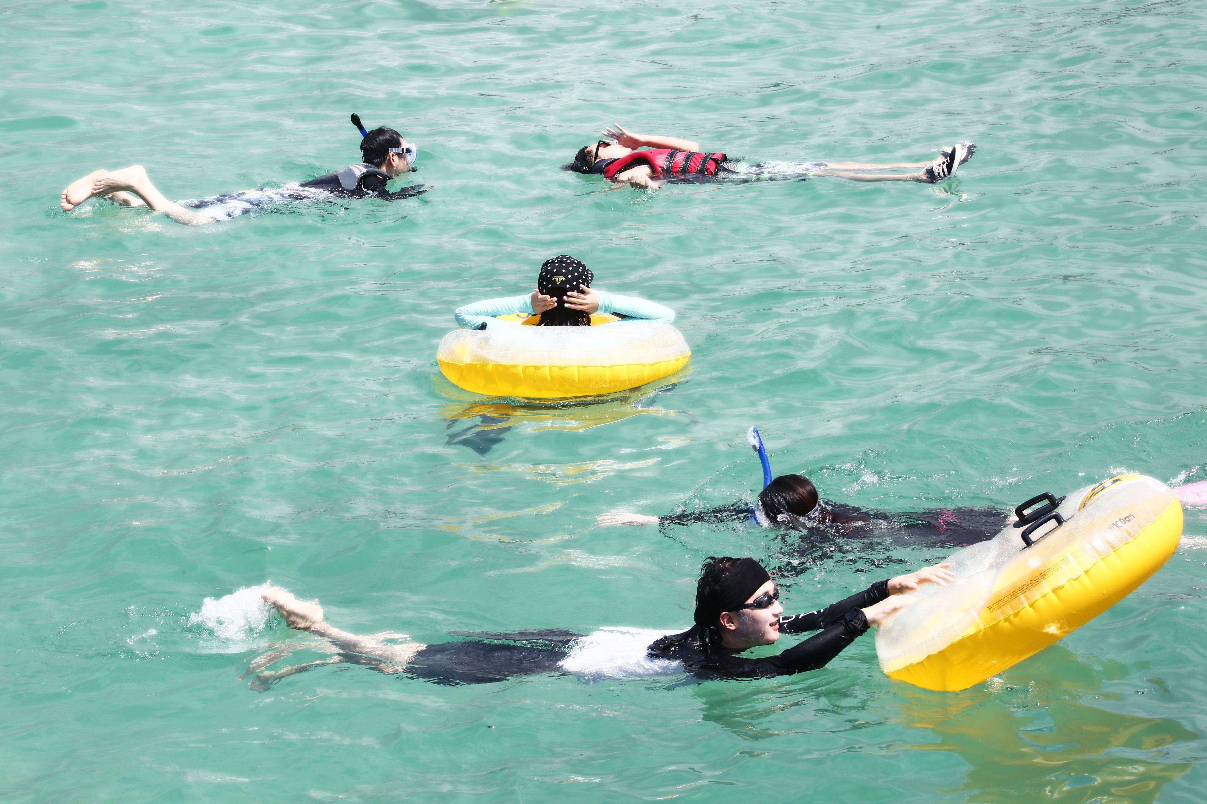 Un groupe de personnes flottant sur l’eau à l’aide de bouées gonflables.