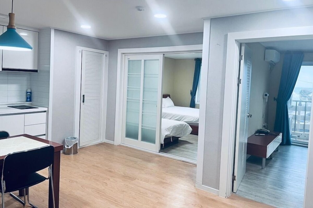 A modern hotel room with a kitchenette, a bed with a view, and a separate dining area.