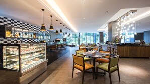 A modern restaurant with checkered wall decor, glass display cases, and a variety of seating options. - Geno Hotel (Shah Alam)