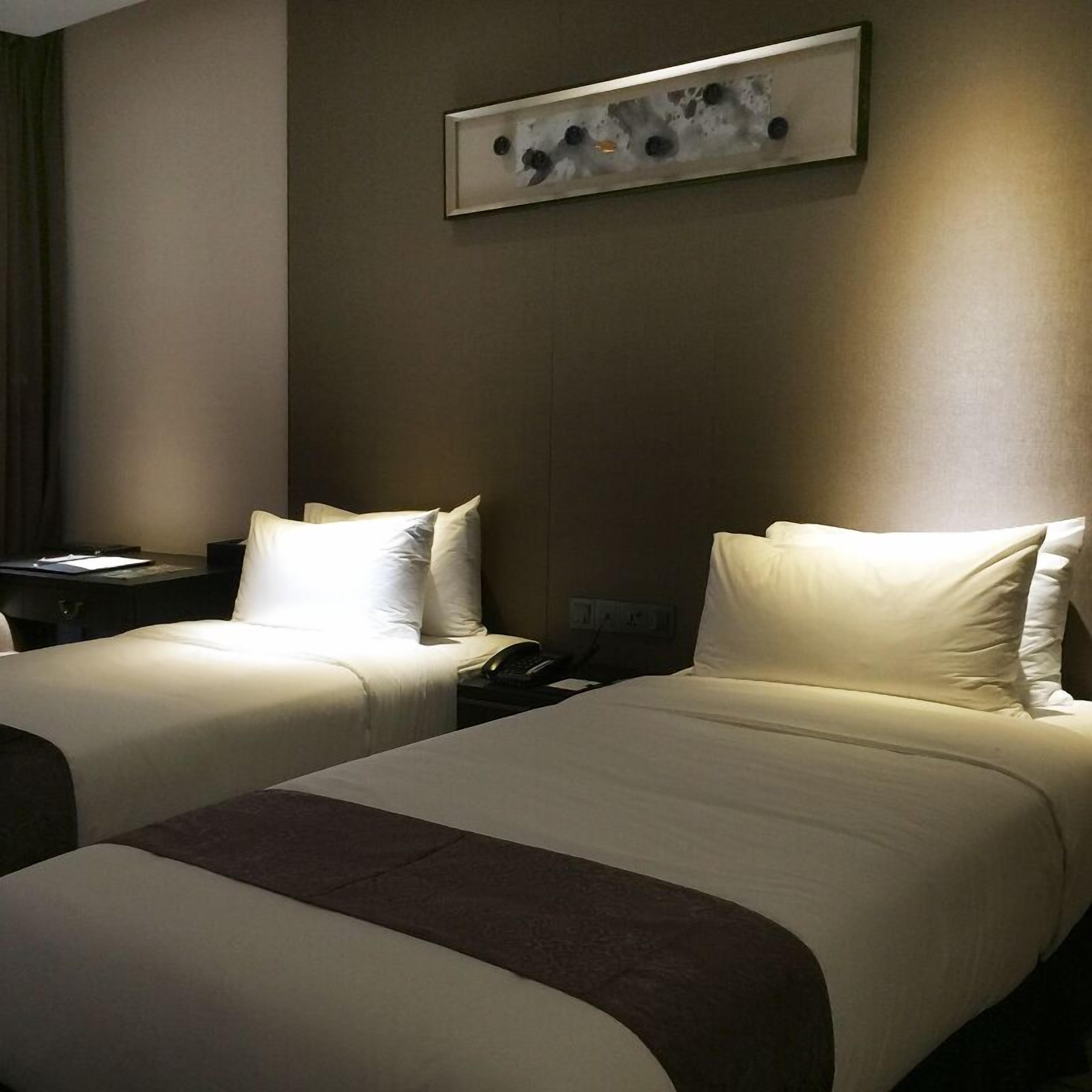 A hotel room with two beds, a desk, and a phone.