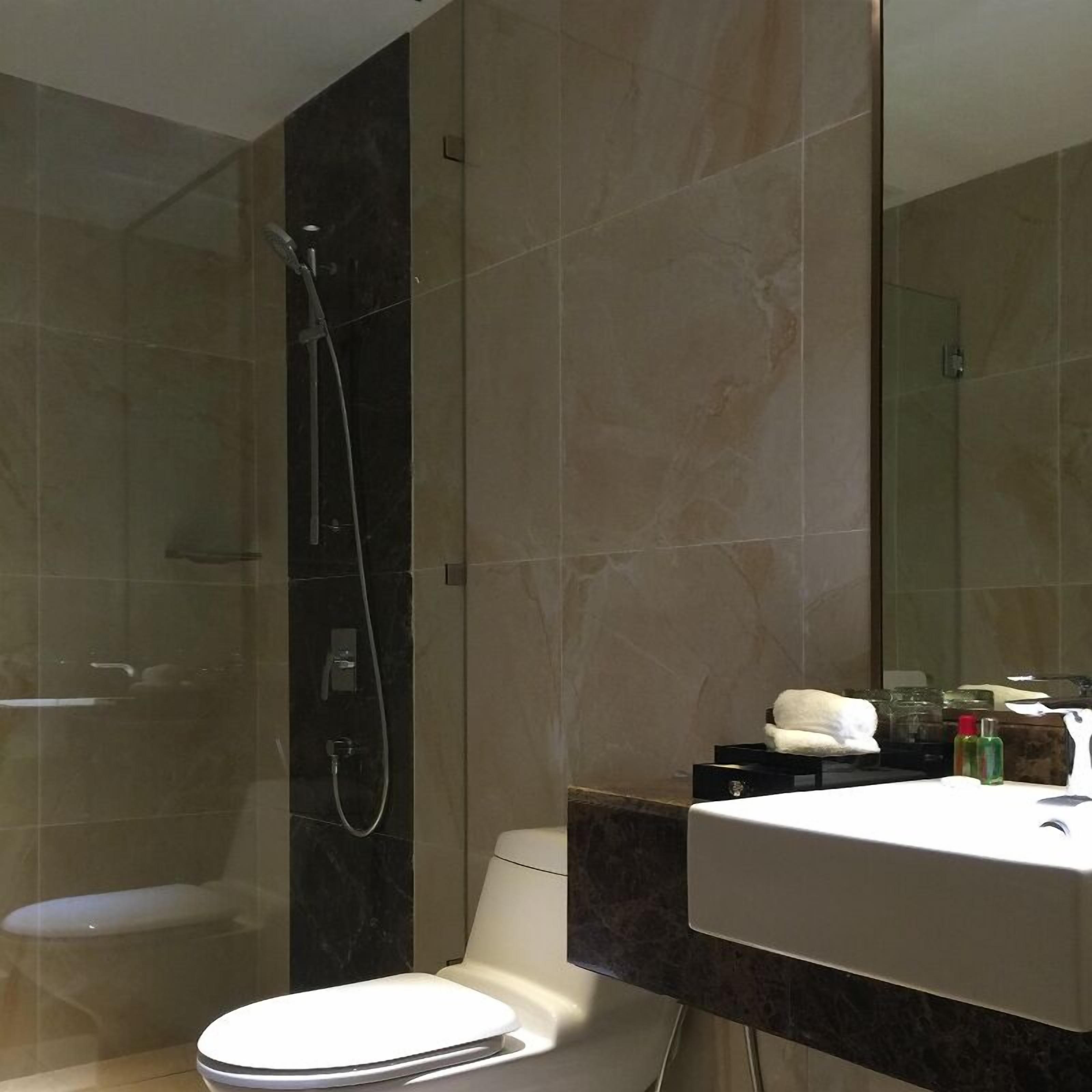 A modern bathroom with a toilet, a sink, and a large mirror.