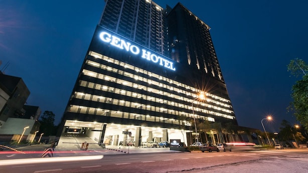 A modern hotel building with a prominent sign reading "GENO HOTEL" at night. - Geno Hotel (Shah Alam)