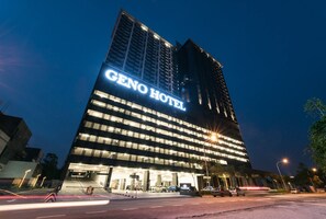 A modern hotel building with a prominent sign reading "GENO HOTEL" at night. - Geno Hotel (Shah Alam)
